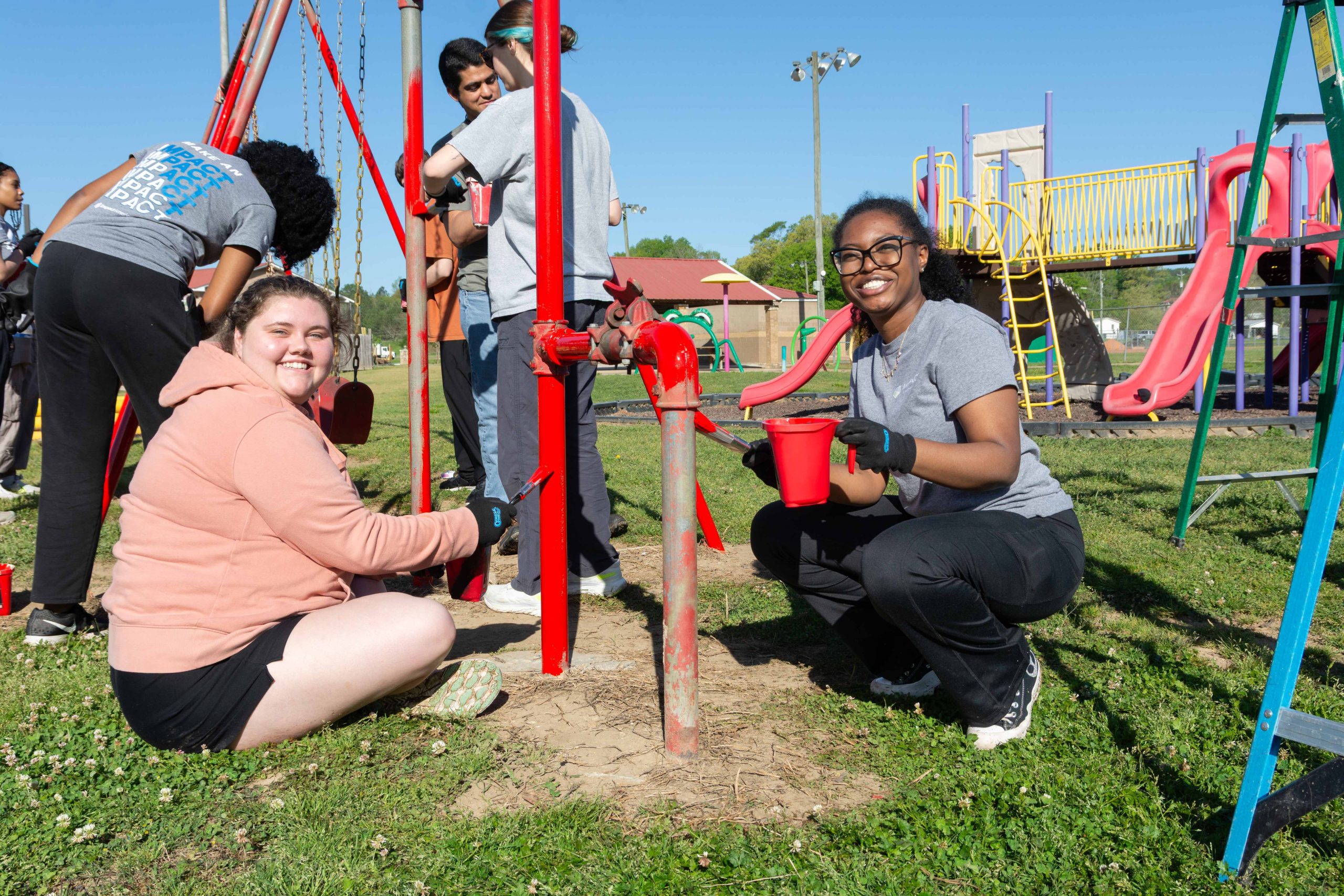 Volunteers working together outdoors, planting or cleaning an area as part of a community service project under a United Way Hands On event.
