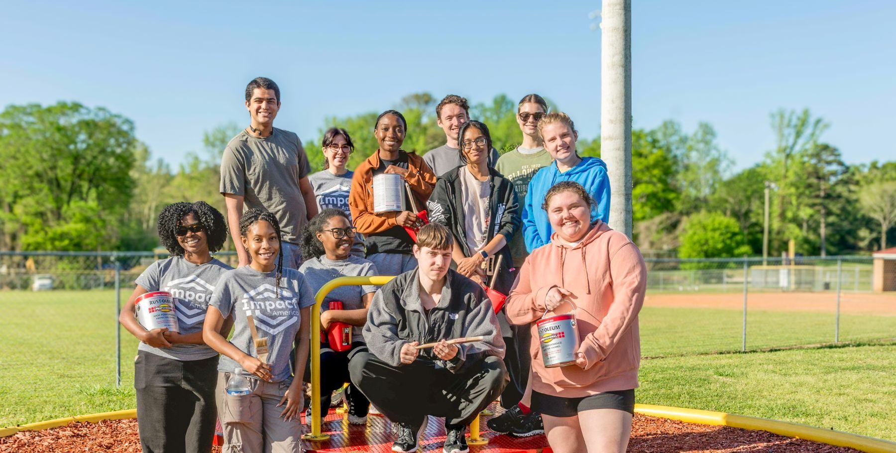Volunteers with United Way Hands On wearing Impact America shirts clean up a playground