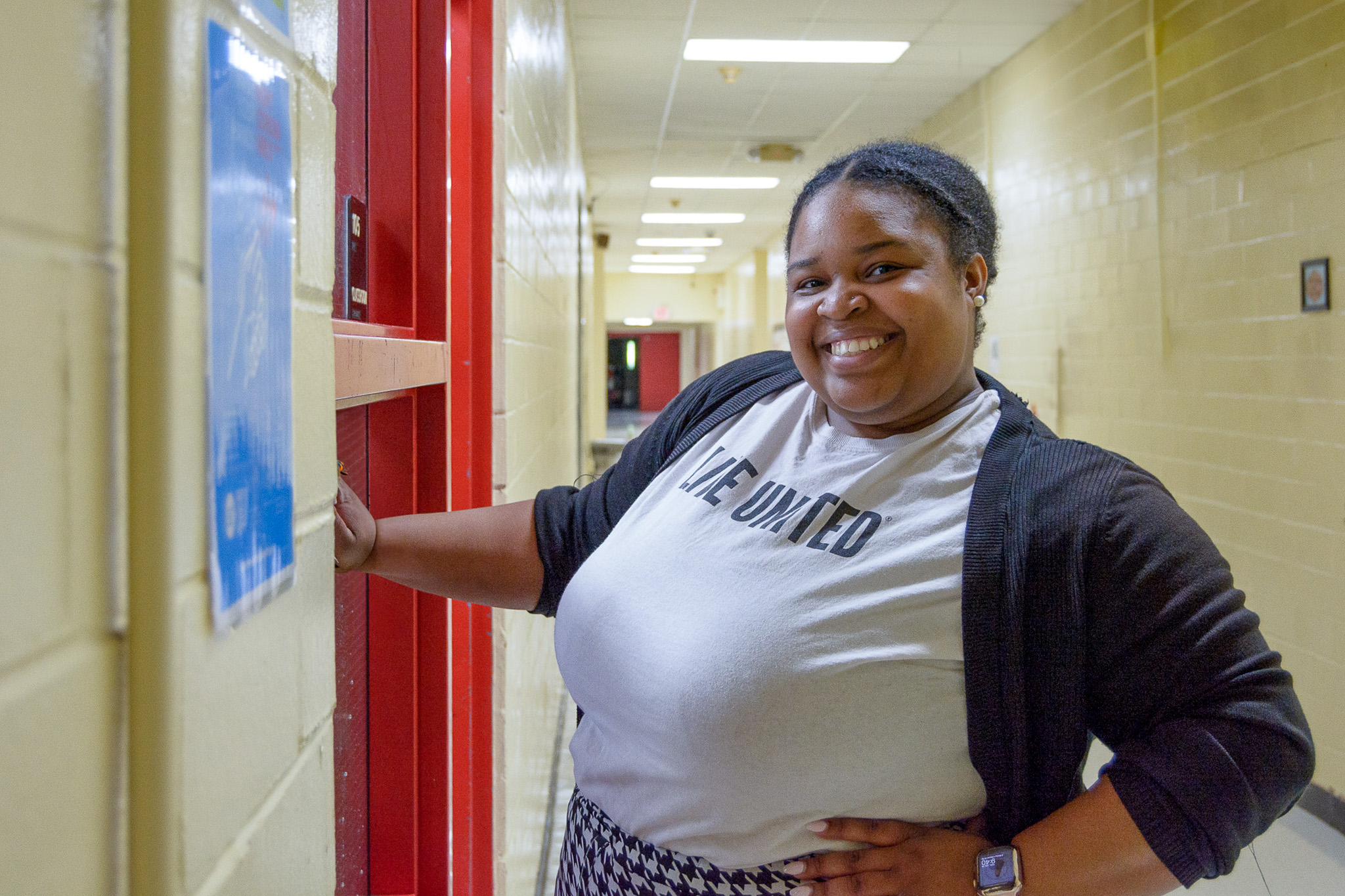 A smiling United Way staff member wearing a “Live United” shirt poses in a school hallway during a back-to-school volunteer project.